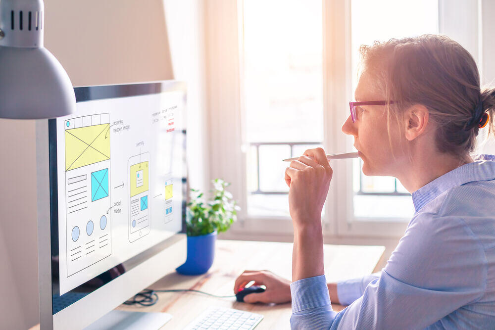 UXUI female web designer stares at screen with wireframes