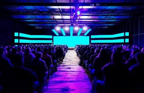 Full conference event space with blue and purple spotlights.